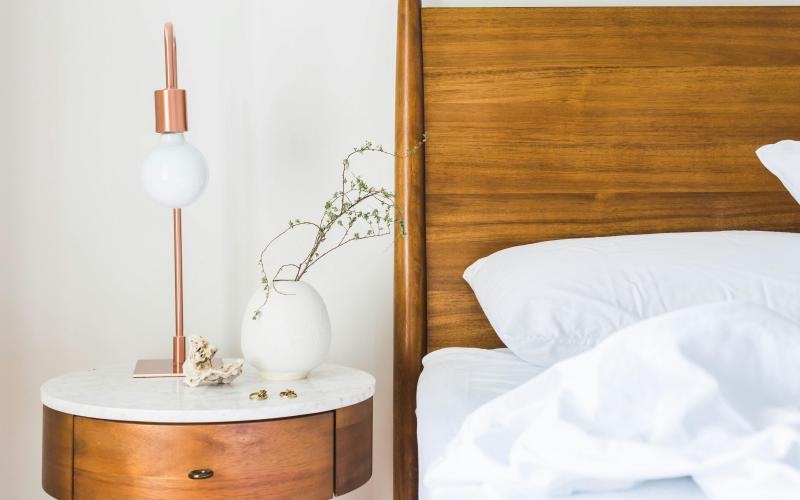 a bed with a lamp and a vase with flowers on it