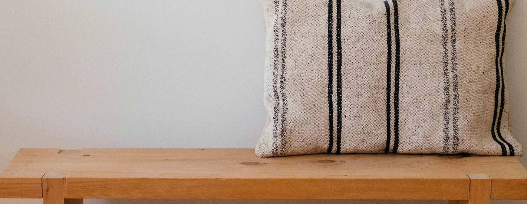 a wooden bench with a striped pillow on it
